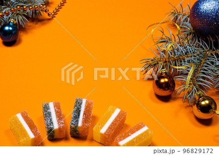 Marmalade jellies and spruce twig with a ribbon and a toy on a yellow background. A banner on a red background with a place for copyspace text. Marmalade jellies and spruce twig with a ribbon and a toy on a yellow background. A banner on a red background with a place for copyspace text. 96829172