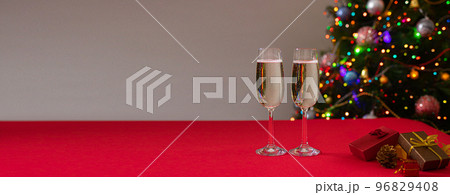 New Year's photo glasses on a red table with champagne on the background of the Christmas tree with lights and sides. Holiday and bull year. Banner New Year's photo glasses on a red table with champagne on the background of the Christmas tree with lights and sides. Holiday and bull year. Banner 96829408
