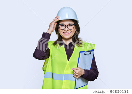 Professional woman in safety vest helmet holding clipboard on white background 96830151