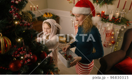 Daughter helps mom to decorate Christmas tree 96830315