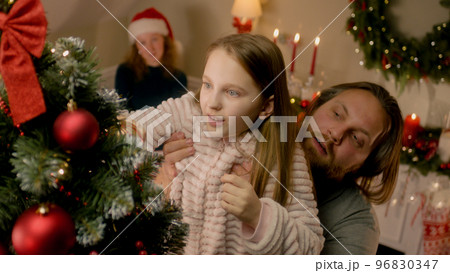 Father lift his daughter up to put Christmas ball on tree Father lift his daughter up to put Christmas ball on tree 96830347