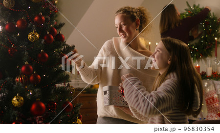 Daughter with mom decorating Christmas tree 96830354