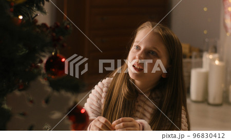 Young girl decorates Christmas tree Young girl decorates Christmas tree 96830412