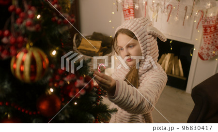 Child lick candy near decorated Christmas tree Child lick candy near decorated Christmas tree 96830417