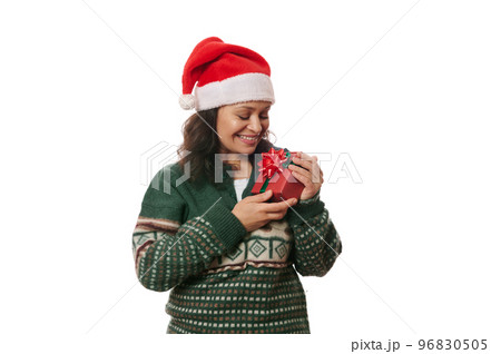 Middle-aged African American pretty woman wearing Santa hat and warm green woolen Xmas patterned sweater, rejoicing at Christmas present, she holds in her hands, isolated on white background. Ad space Middle-aged African American pretty woman wearing Santa hat and warm green woolen Xmas patterned sweater, rejoicing at Christmas present, she holds in her hands, isolated on white background. Ad space 96830505