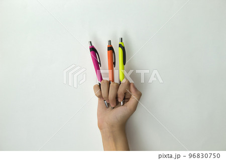 hand of girl showing three color pens between the fingers on white background 96830750