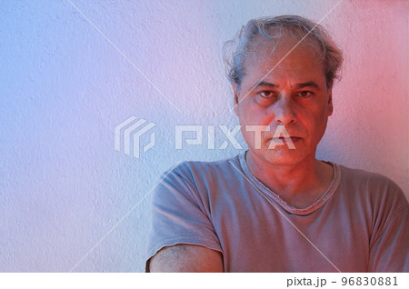 portrait with copy space of mature man with ambient color lights on a white background looking straight ahead with a serious expression 96830881