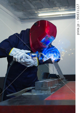 worker woman welding metal with helmet and overalls worker woman welding metal with helmet and overalls 96831127
