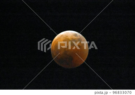 皆既月食。夜空に浮かぶオレンジ色の地球の影と、上部が僅かに日光が漏れ光る光る月。 96833070