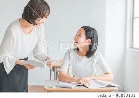 夏期講習で個別指導する塾講師・先生と質問する笑顔の受験生・小学生・中学生・高校生の生徒（子供） 96833133