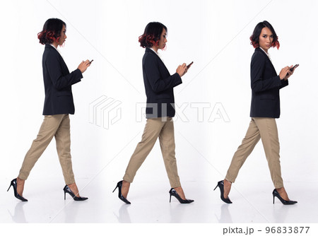 Full length 20s Asian Woman wear formal Business dress blazer high heel shoes. Black short curl hair female walking happy smile hold smart phone, walk forward left right over white background isolated 96833877