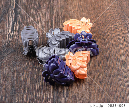 Several multi -colored female hair clips on a wooden background. Several multi -colored female hair clips on a wooden background. 96834093