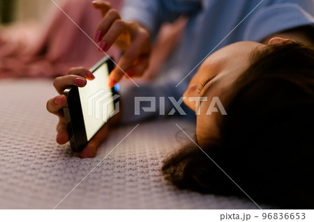 寝ながらスマホをする女性 96836653