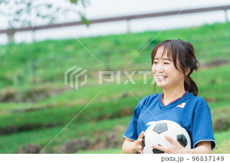 サッカーボールを持ちながら笑顔でサッカー観戦するサッカーファン・サポーター 96837149