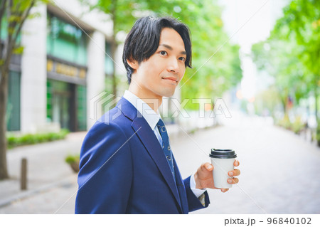 コーヒーを片手にオフィス街を歩くビジネスマン コーヒーを片手にオフィス街を歩くビジネスマン 96840102