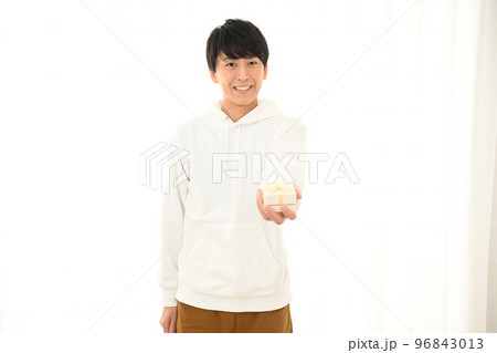 プレゼントの箱の包みを差し出す若い男性 96843013