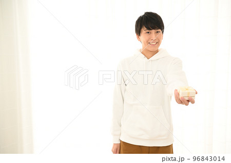 プレゼントの箱の包みを差し出す若い男性 96843014