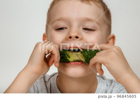 A little boy eats a fresh green cucumber. A little boy eats a fresh green cucumber. 96845605