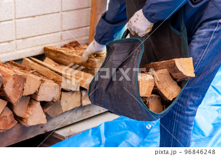 薪ストーブ用の薪を運ぼうとしている男性 96846248
