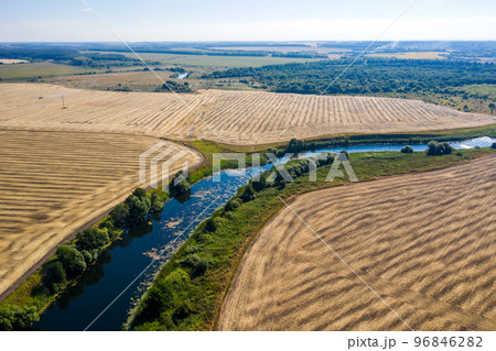 aerial photography of a bend in a river flowing through mown fields 96846282