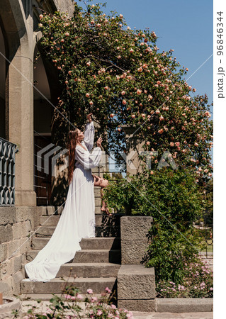 a beautiful woman in a white flowing long dress stay near a beautiful field with pink flowers rear view a beautiful woman in a white flowing long dress stay near a beautiful field with pink flowers rear view 96846344