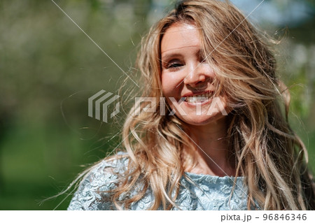 Portrait of a blonde in the park. Beautiful woman with long blond hair in a blue dress. Portrait of a blonde in the park. Beautiful woman with long blond hair in a blue dress. 96846346