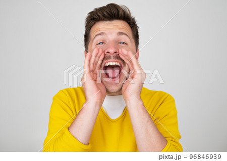 Excited young caucasian man shouting with hands cupped around mouth  96846939