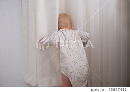 Little baby child playing with the white curtain, child have fun indoor 96847451