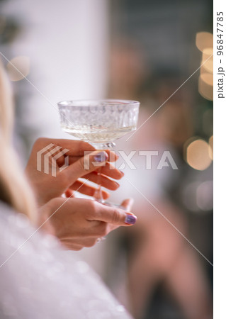The hands of a woman hold a glass of champagne on a background of golden beke. The concept of the holiday, Christmas, new year, birthday. The hands of a woman hold a glass of champagne on a background of golden beke. The concept of the holiday, Christmas, new year, birthday. 96847785