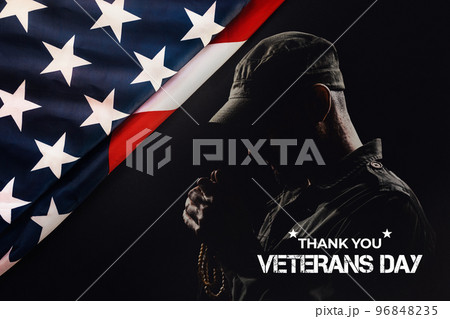 National American holidays. The silhouette of a male praying soldier on a black background with an American flag. The concept of Veterans Day National American holidays. The silhouette of a male praying soldier on a black background with an American flag. The concept of Veterans Day 96848235