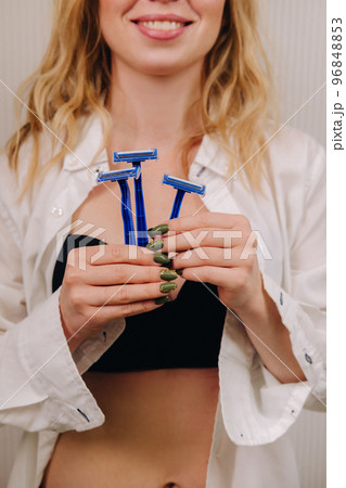 A beautiful portrait of a feminine woman in a shirt and underwear with a set of razors in her hand A beautiful portrait of a feminine woman in a shirt and underwear with a set of razors in her hand 96848853