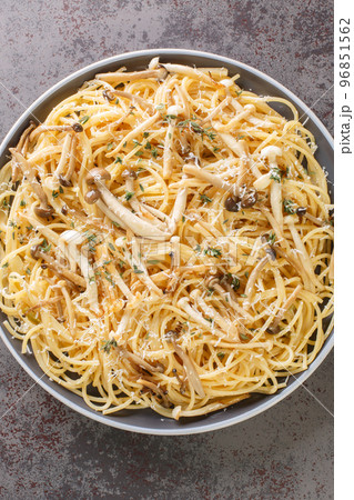 Pasta with brown and white beech mushrooms in a creamy mushroom sauce and thyme closeup on plate. Vertical top view 96851562
