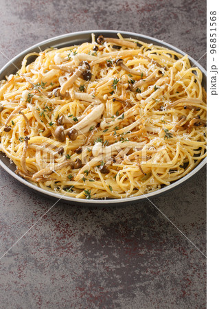 Spaghetti cooked with white and brown beech mushrooms with creamy sauce and thyme close-up in a plate. vertical 96851568