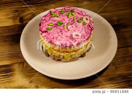 Traditional russian salad "Herring under a fur coat" (shuba) on wooden table. Layered salad with herring, beets, carrots, onions, potatoes and eggs 96851886