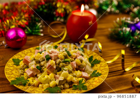 Tasty festive salad, Christmas decor and candle on wooden table Tasty festive salad, Christmas decor and candle on wooden table 96851887