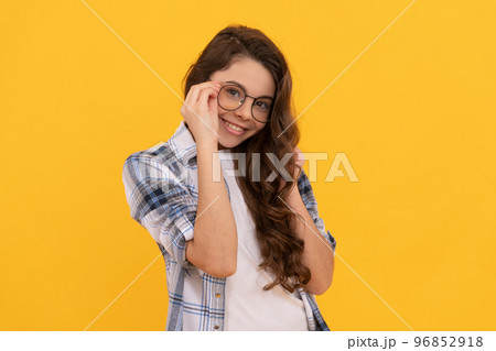 positive teen girl in checkered shirt and glasses on yellow background 96852918