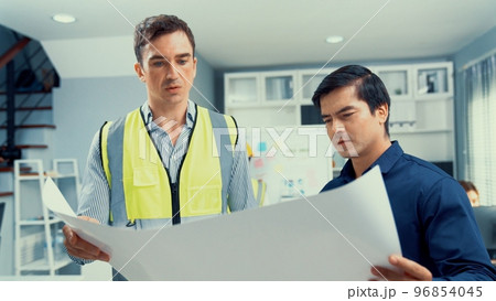 Competent investor investor discuss and brainstorm with engineers on blueprint. 96854045