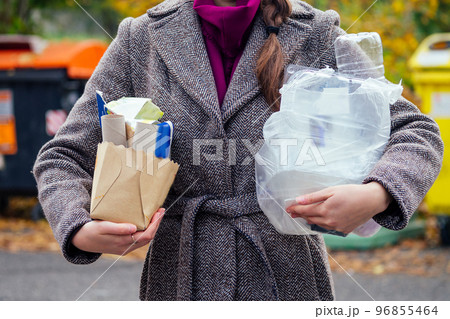 Aware woman separating paper from other waste, putting it into green container to save natural resources in Prague Chezh 96855464