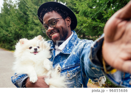 african american man making self portrait with fluffy spitz in summer spring park african american man making self portrait with fluffy spitz in summer spring park 96855686