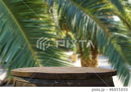 Jungle table background. Rustic wooden table against the backdrop of tropical plants, palms and jungle.  96855850