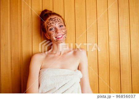 redhaired ginger young woman peeling face with brown sugar in traditional russian banya.steaming and self-care in finnish sauna 96856037
