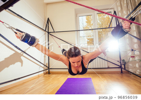 Sporty young caucasian woman doing stretching exercises of full body muscles workout on stretch aerobic aero strap in gym,yogi mat 96856039