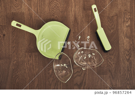 A close-up view from above of a split transparent cup with soup and brushes with a dustpan for cleaning. The concept of home cleaning in the apartment. High quality photo 96857264