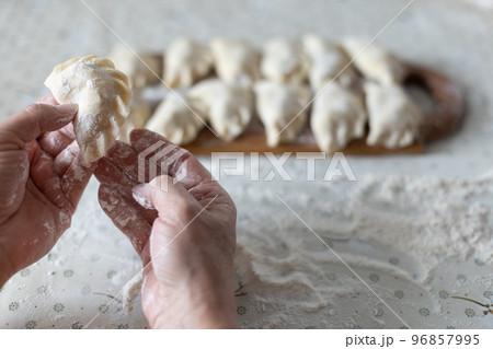 Homemade raw dumplings with cherries. Womans hands cooking dumplings with cherries. Homemade raw dumplings with cherries. Womans hands cooking dumplings with cherries. 96857995
