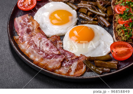 Tasty breakfast consists of eggs, bacon, beans, tomatoes, with spices and herbs 96858849