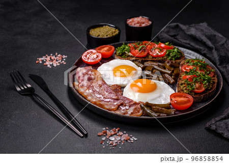 Tasty breakfast consists of eggs, bacon, beans, tomatoes, with spices and herbs 96858854