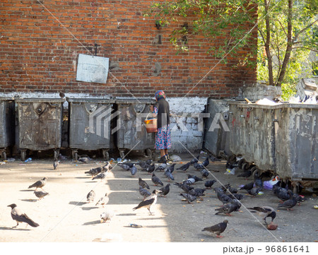 A beggar woman by the trash cans. Old lady with bucket A beggar woman by the trash cans. Old lady with bucket 96861641