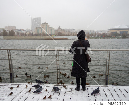 Woman feeds birds in heavy snow. 96862540