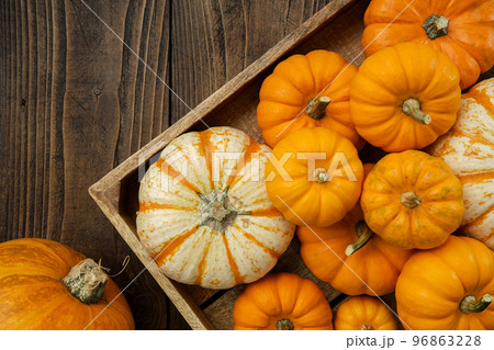 Several small pumpkins in a wooden crate on a kitchen table. Several small pumpkins in a wooden crate on a kitchen table. 96863228