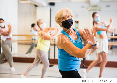 Active mature woman in a protective mask practices energetic swing in the studio 96864171